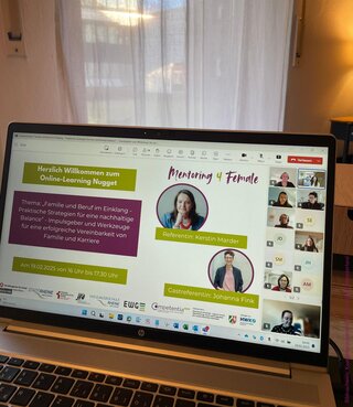 Das Bild zeigt ein Laptop-Display mit einer Online-Konferenz über Balance zwischen Familie und Beruf. Teilnehmer sind in kleinen Fenstern sichtbar.