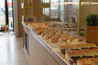 Das Bild zeigt ein Buffet mit köstlichen Desserts, darunter Obstsalate und verschiedene Kuchen, appetitlich angerichtet in Gläsern und auf Platten.