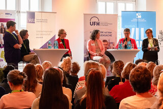 Das Bild zeigt eine Diskussionsrunde mit mehreren Frauen und Männern auf einer Bühne, die über Unternehmerinnen und deren Herausforderungen sprechen.