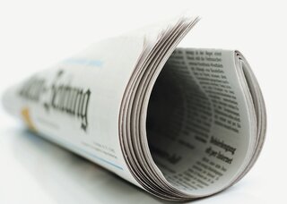 Das Bild zeigt eine aufgerollte Zeitung mit gut lesbarem Text und einer klaren typografischen Gestaltung.