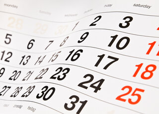 Das Bild zeigt einen Kalender mit deutlich sichtbaren Daten, einschließlich Montag bis Samstag, in Schwarz und Rot.