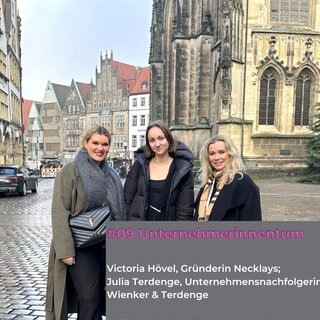 Das Bild zeigt drei Frauen vor einer historischen Kulisse. Sie lächeln in die Kamera, während sie modische Outfits tragen.